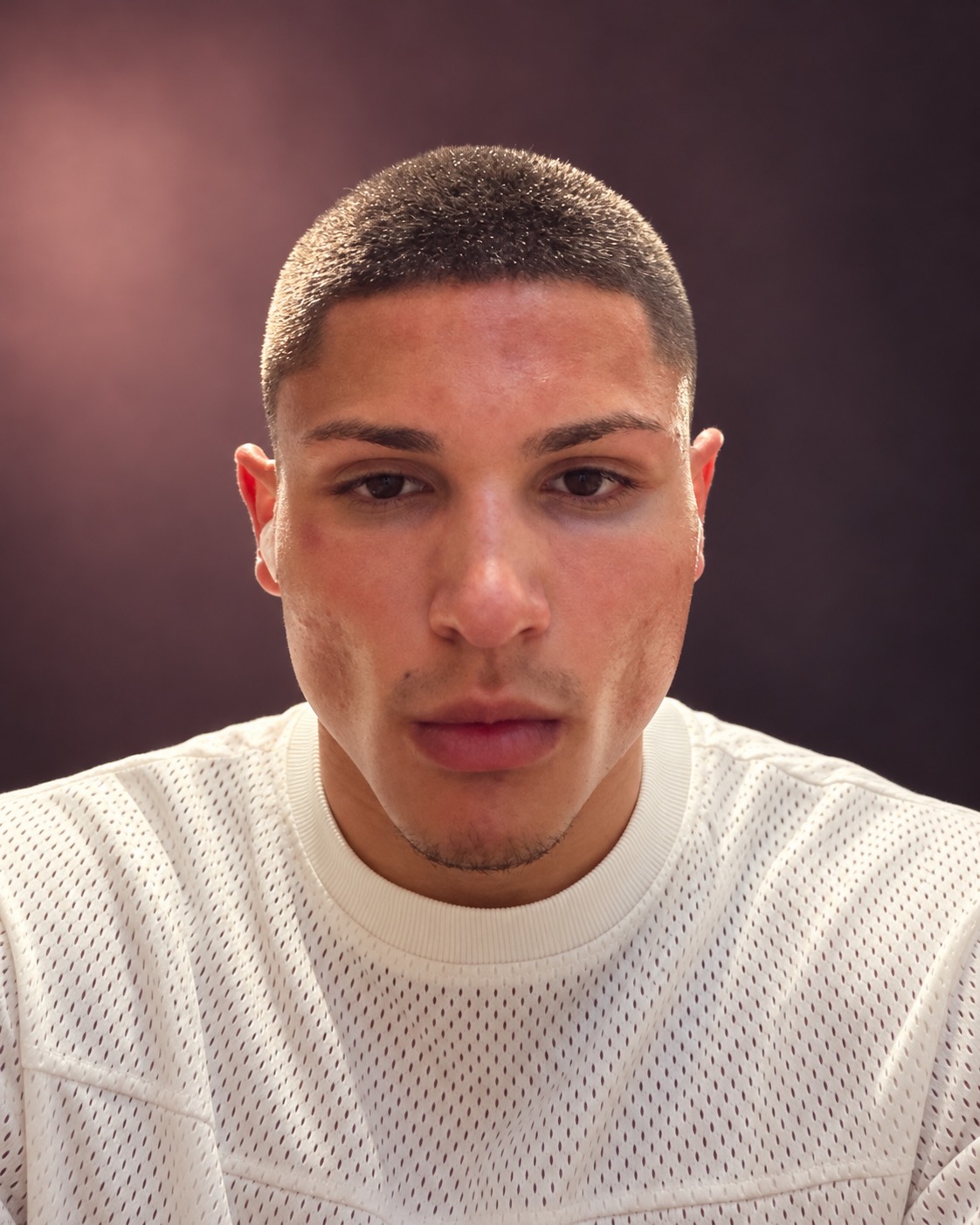 Marquis Jackson, partner at M Studio, wearing a white textured shirt against a plum studio background